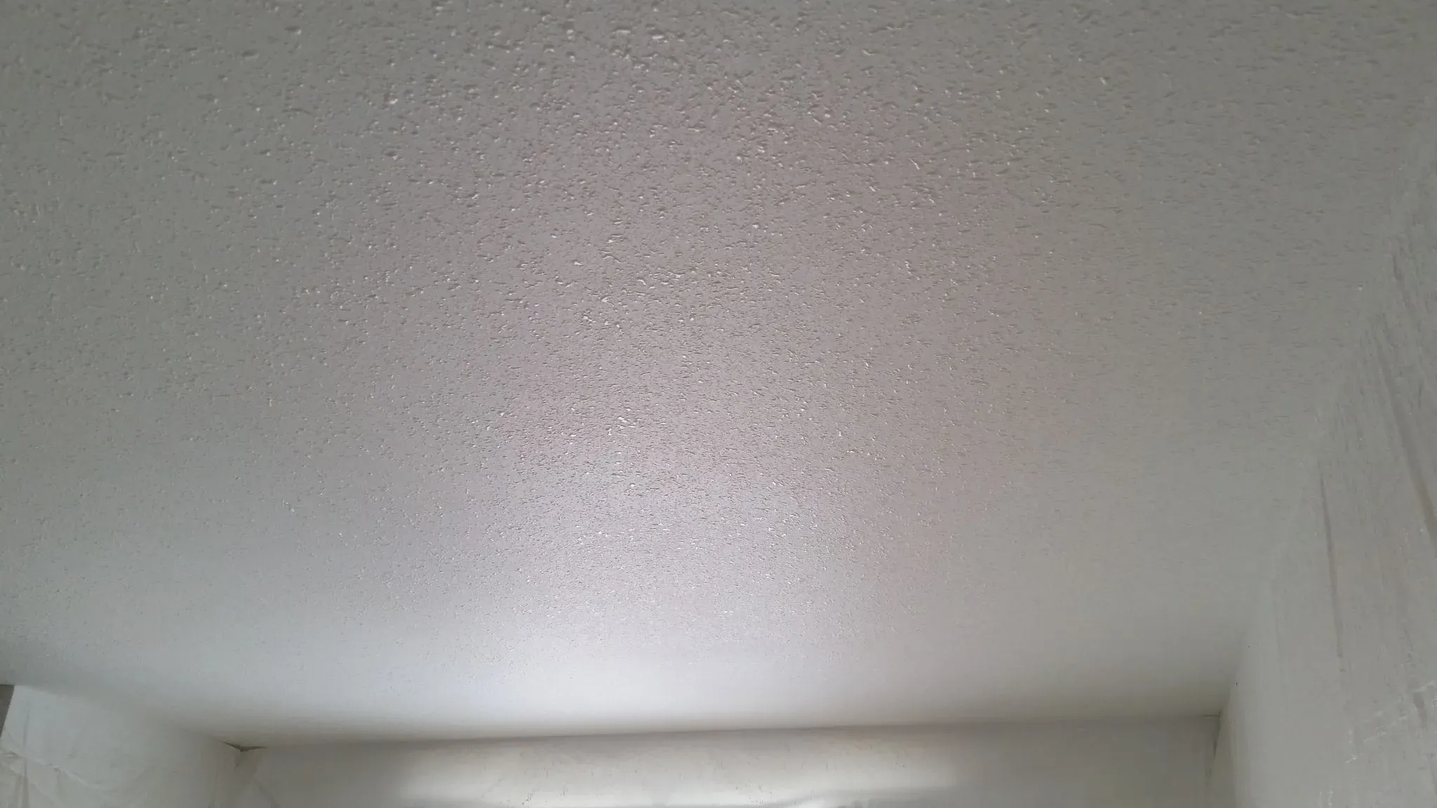 Finished living room with smooth walls and vaulted ceiling by Wild West Drywall